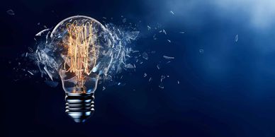 A light bulb shattering with glowing filaments inside against a blue background.