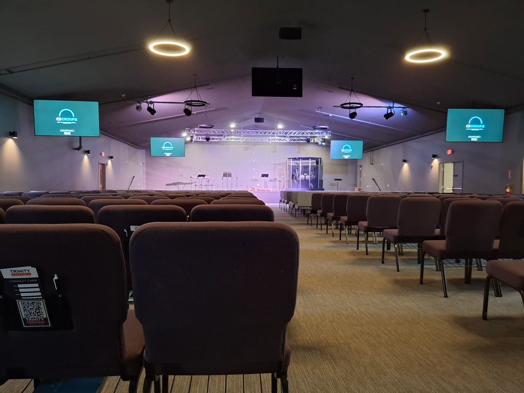 Interior view of a modern church sanctuary with rows of chairs and multiple screens.