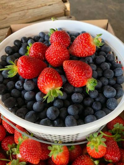 A bowl filled with fresh strawberries on top of blueberries.