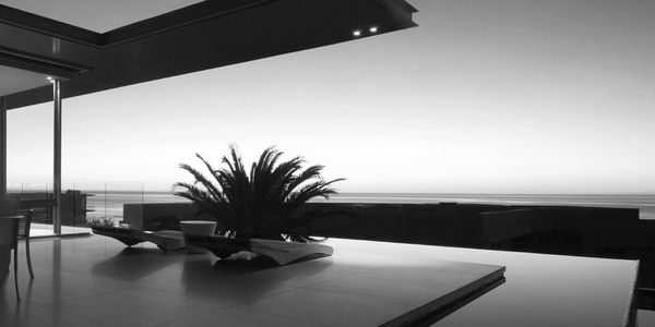 Modern patio with lounge chairs and ocean view at dusk.