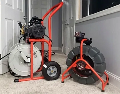 Two large industrial pipe inspection cameras on carpet indoors.