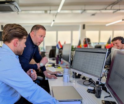 Two men collaborating and discussing data on a computer screen in an office.