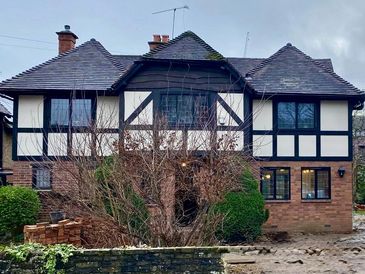 Two-story house with timber framing and brick on the ground floor.