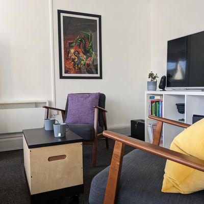 The counselling room: two chairs, two mugs and table in between. Fantasy art in a  frame on the wall