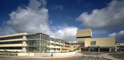 Modern hospital building under a partly cloudy sky.