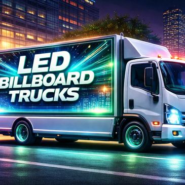 A bright LED billboard truck illuminated at night in a city setting.