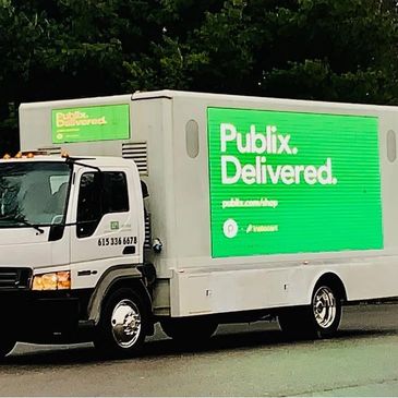 Publix delivery truck with bright green advertisement on its side.