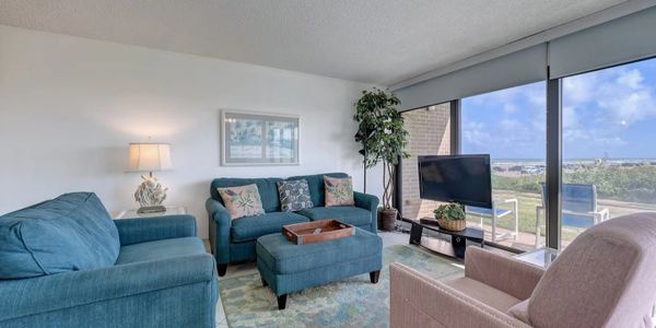 Cozy living room with teal furniture and large windows overlooking a scenic view.