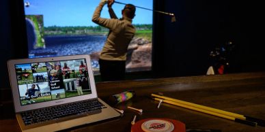 Man playing golf indoors with a simulator.