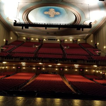 Empty theater with red seats and an ornate ceiling.