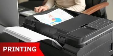 A printer producing a colorful chart on paper in an office setting.