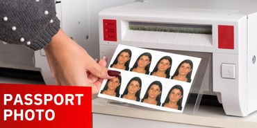 Person printing multiple passport-sized photos from a printer.