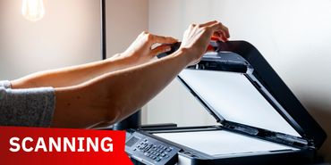Hands placing a document on a scanner for scanning.