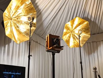Vintage camera setup with gold reflective umbrella lights in a studio.