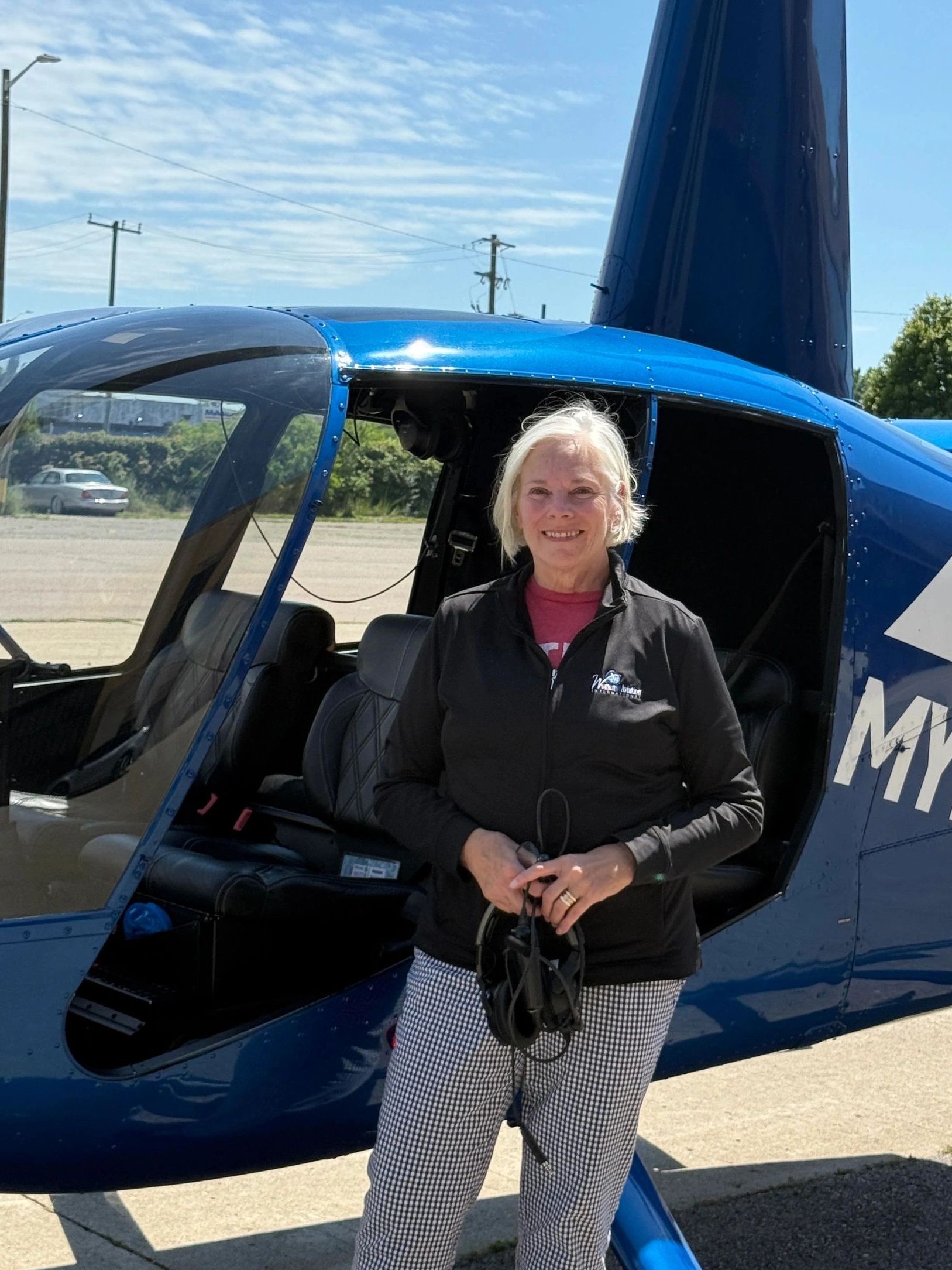 Smiling woman in front of a blue helicopter.