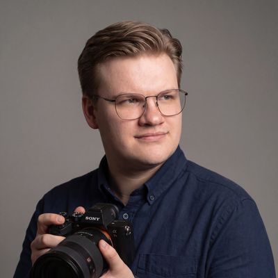 Een portretfoto van Milan De Clercq, zaakvoerder, met camera in de hand.