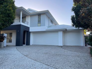 Modern two-story house with white garage doors and driveway.