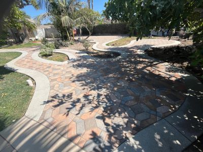Curved stone pathway with garden beds and tropical plants in a sunny backyard.