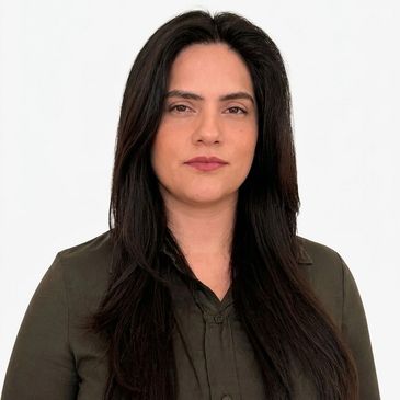 Serious woman with long dark hair wearing a dark green button-up shirt.