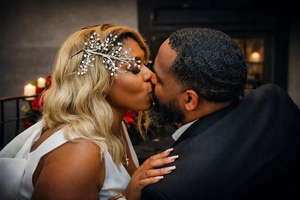 A couple sharing a tender kiss, dressed elegantly for a special occasion.