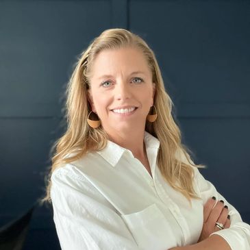 Smiling woman with blonde hair wearing earrings and a white shirt.