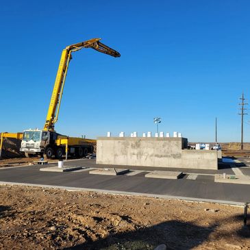 Concrete pump truck working at a construction site under clear blue sky.