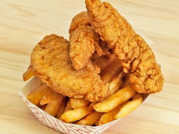 Crispy fried chicken tenders with golden French fries in a paper tray.