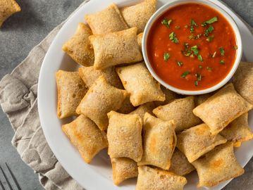 Plate of crispy pizza rolls served with marinara dipping sauce.
