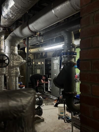 Person inspecting machinery in industrial room.