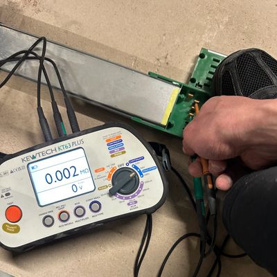 Hand measuring resistance with a KEWTECH KT63 PLUS meter.