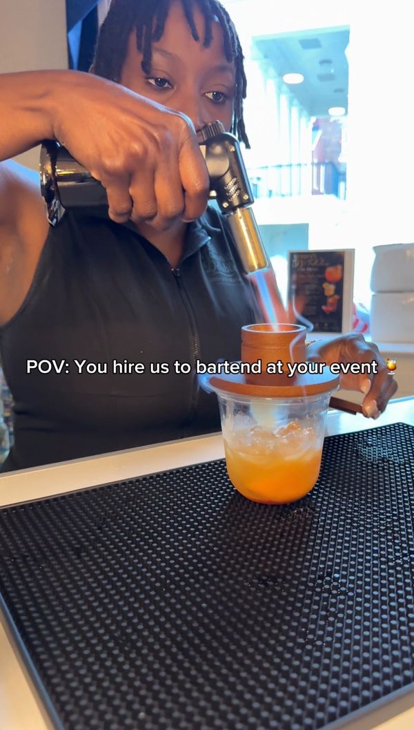 Bartender uses a torch to flame a cocktail at an event.