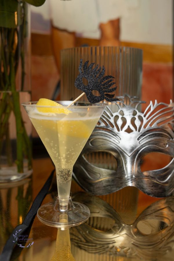 Martini glass with lemon garnish and decorative mask.