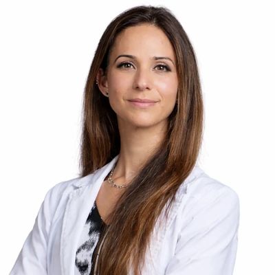 Confident woman in a white lab coat smiling at the camera.