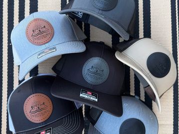 Six stylish caps with mountain logos arranged on a striped surface.