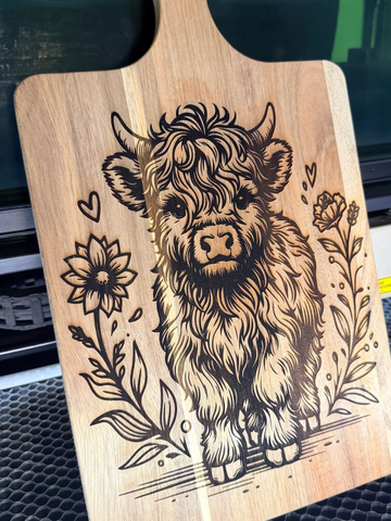 Wooden cutting board engraved with a cute highland calf and floral design.