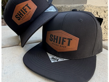 Two black caps with 'SHIFT Speed Shop' logo in brown patch.