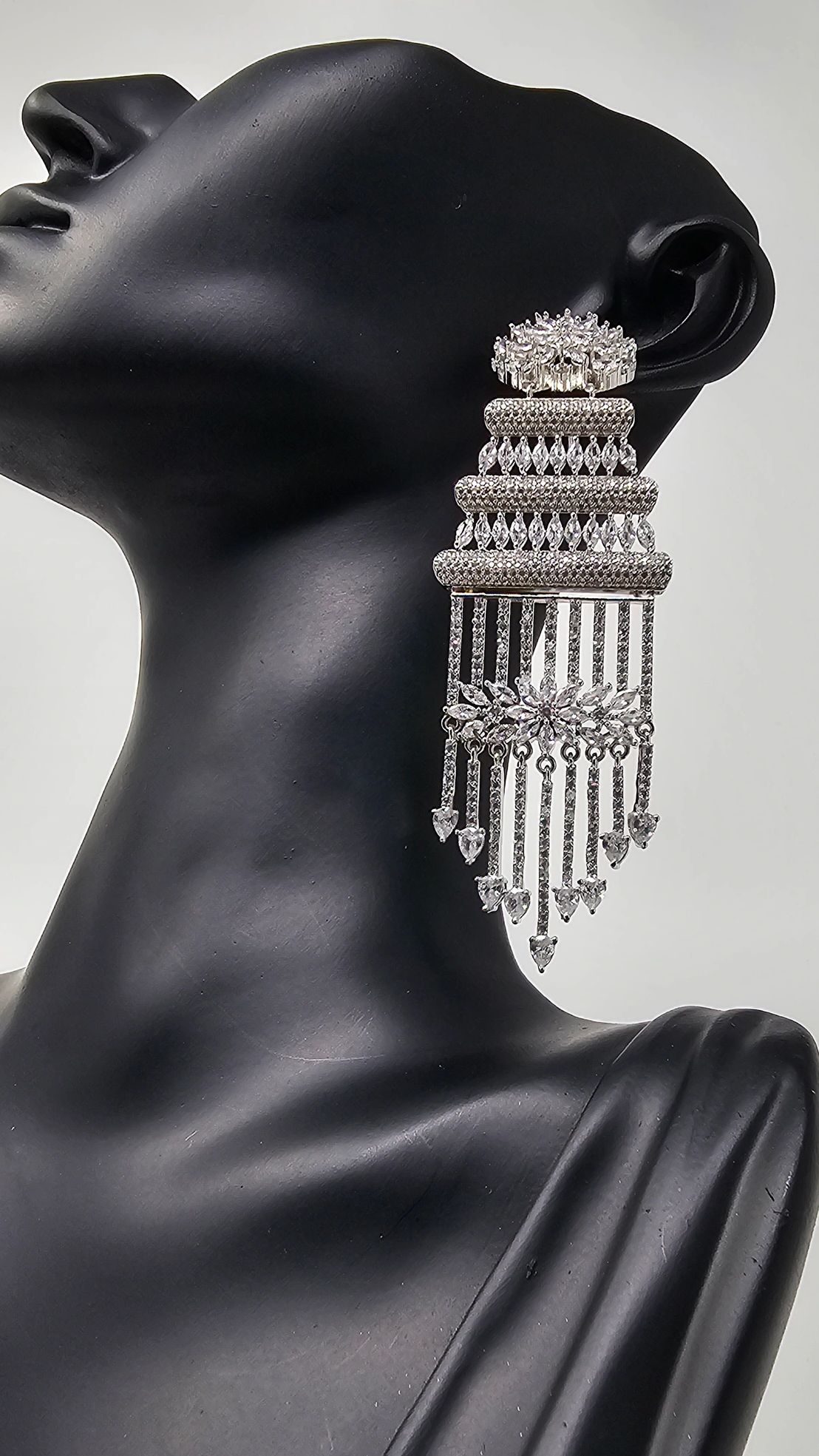 Elegant chandelier-style silver earrings displayed on a black mannequin bust.
