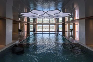Luxurious indoor pool with geometric ceiling light and large windows.