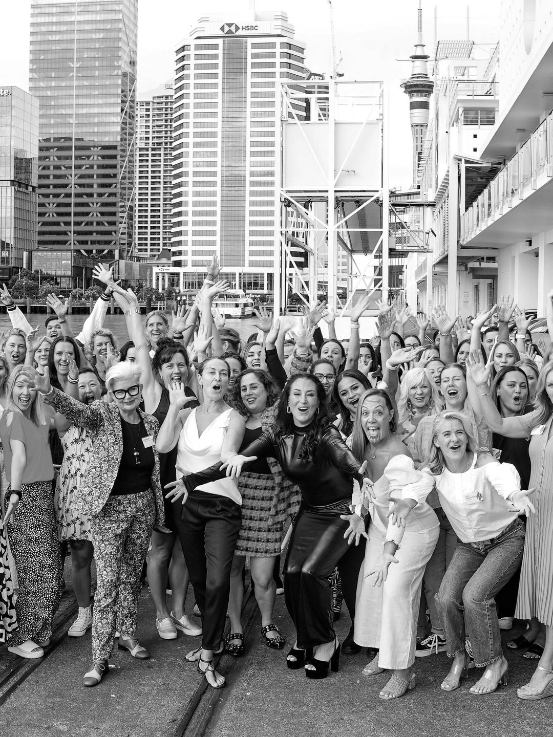 Large group of joyful women posing energetically in an urban setting.