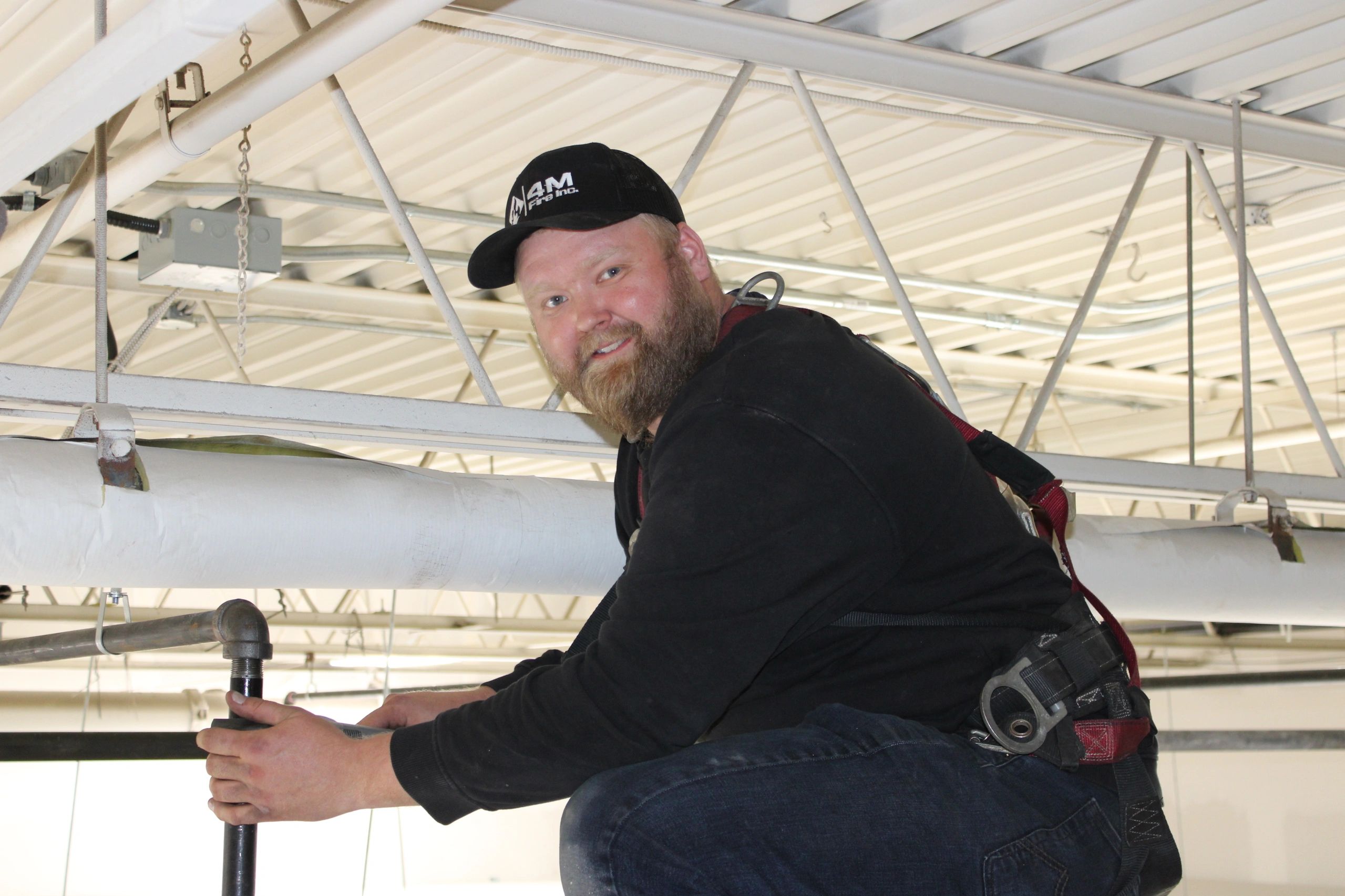 4M Fire technician inspecting overhead sprinkler pipes in a Toronto warehouse