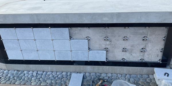 Partially tiled concrete surface with tools nearby.