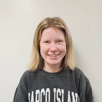 Smiling young woman with blonde hair wearing a Marco Island sweatshirt.