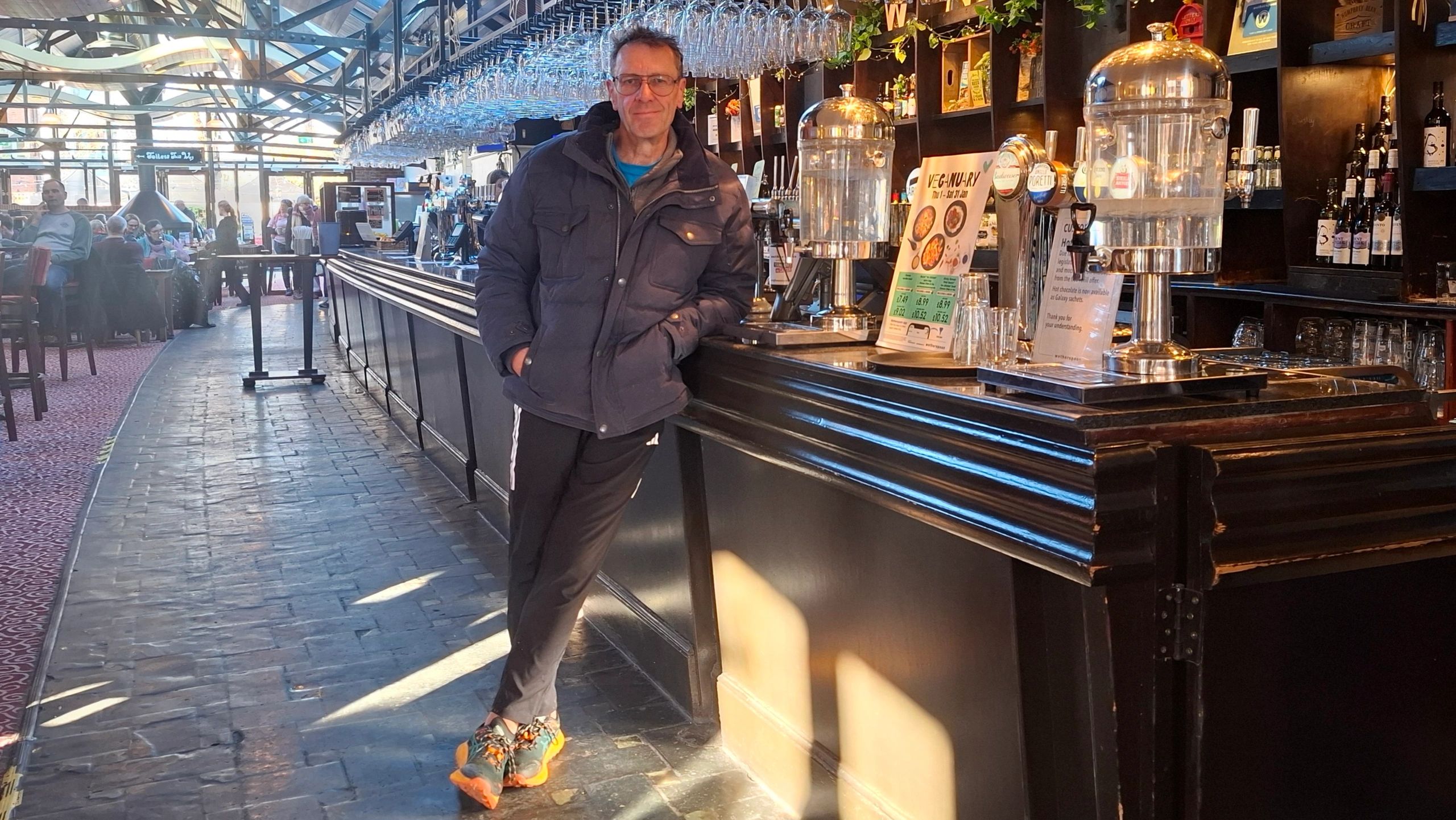 Man leaning on a bar counter in a pub.