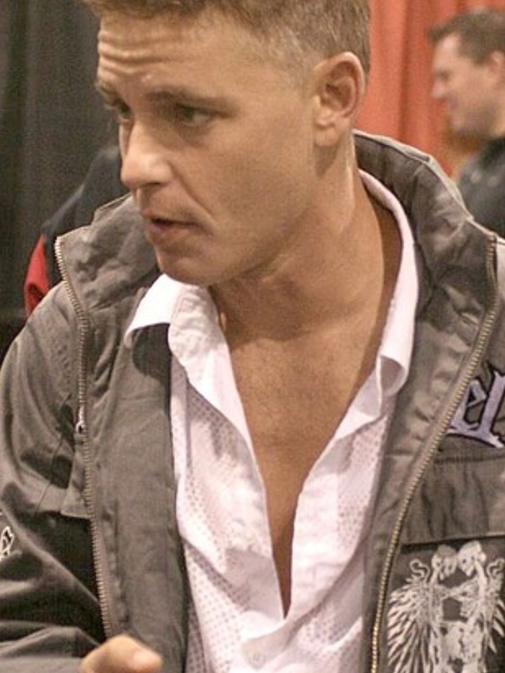 Man with short hair wearing a jacket and white shirt.