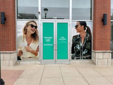 Two smiling women on door posters with leasing information.