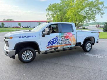 White pickup truck with colorful painting company advertisement.