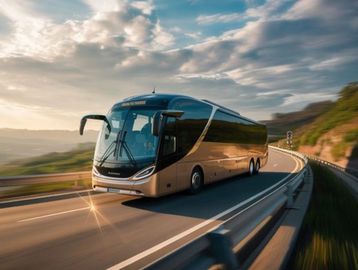 A sleek, modern coach bus driving on a scenic curved highway at sunset.