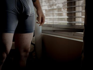 Person standing by window in shorts.