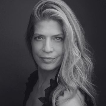 Black and white portrait of a woman with long flowing hair and a confident expression.