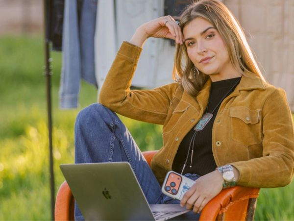 Young woman relaxing outdoors with laptop and phone.